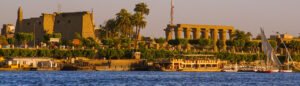 Nile Cruise boat docked near the illuminated Kom Ombo Temple at dusk